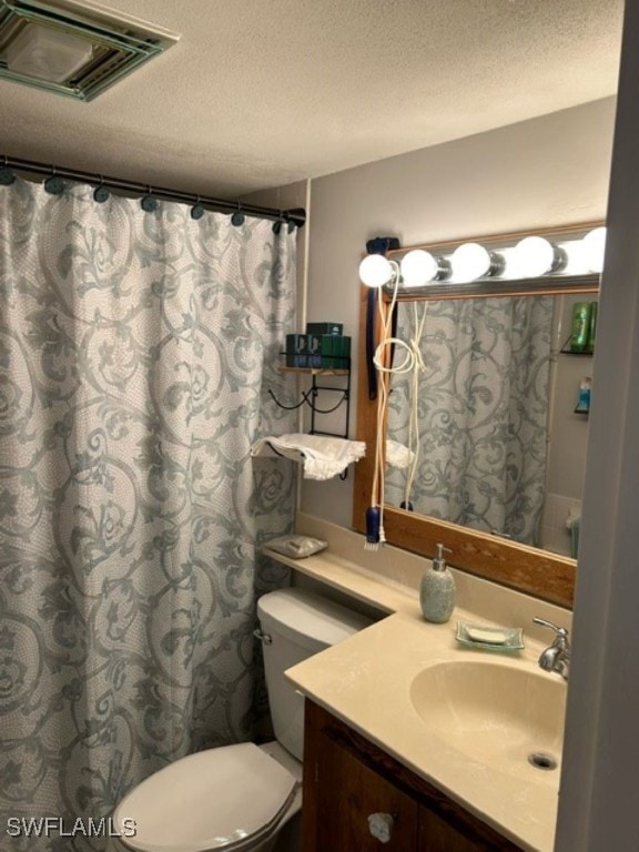 bathroom with vanity, a textured ceiling, toilet, and walk in shower