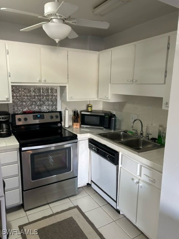 kitchen featuring tasteful backsplash, light tile patterned floors, appliances with stainless steel finishes, white cabinetry, and sink