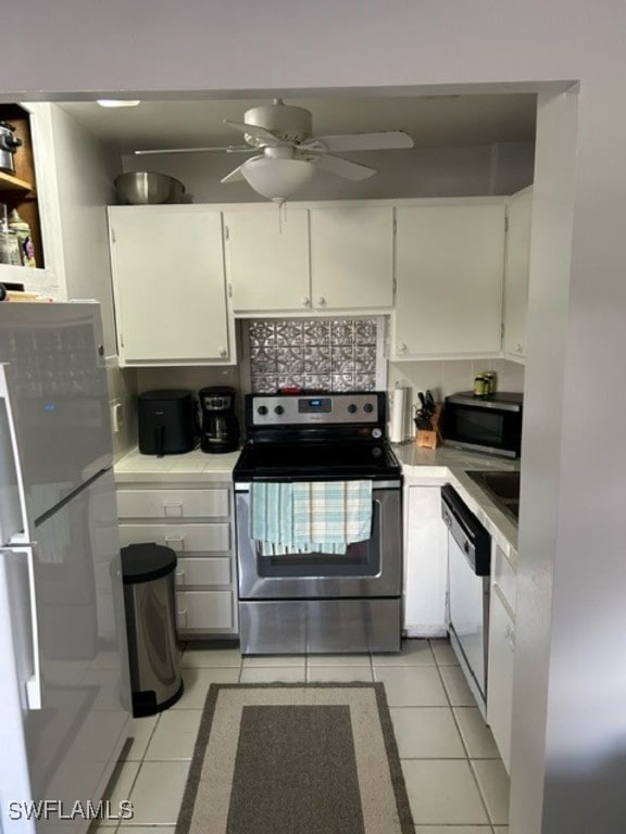 kitchen with appliances with stainless steel finishes, white cabinets, and light tile patterned floors