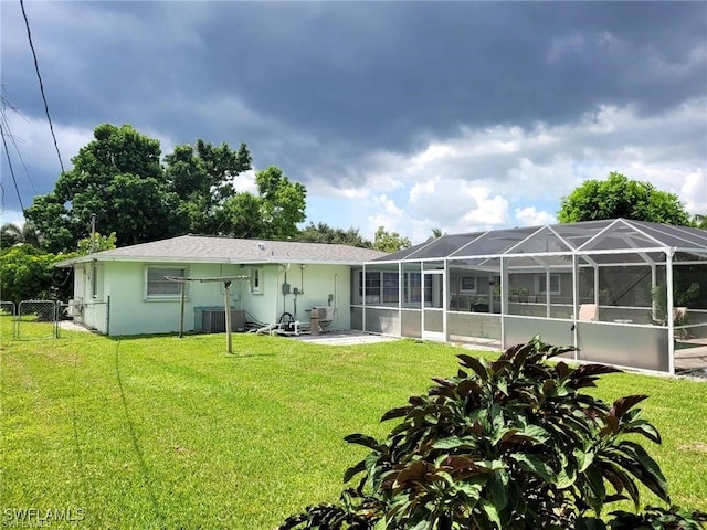 rear view of house with a patio area, a lanai, a lawn, and central AC unit