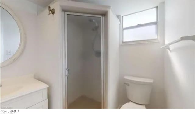 bathroom with toilet, an enclosed shower, and vanity