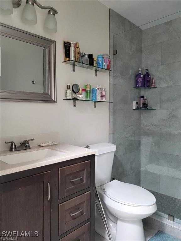 bathroom with vanity, toilet, and a tile shower