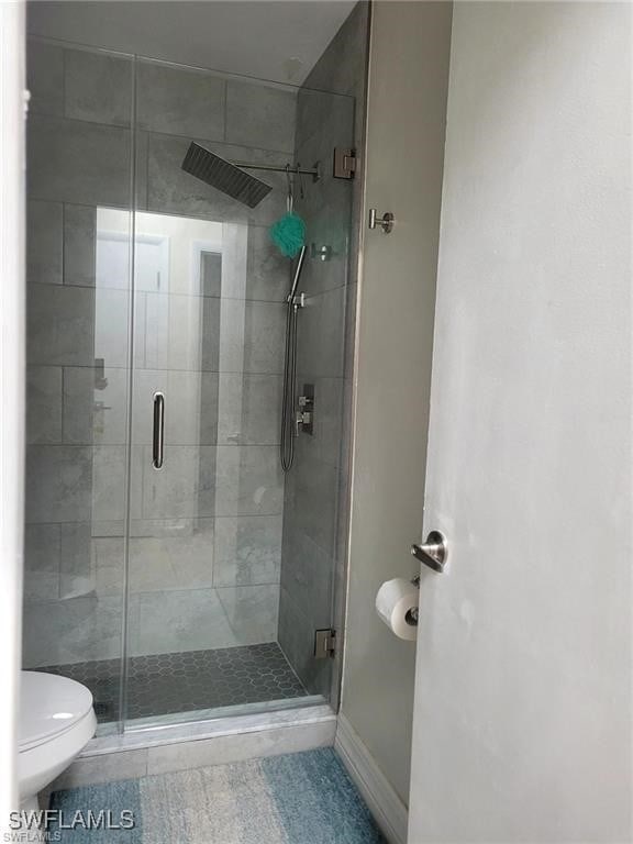 bathroom with toilet and an enclosed shower