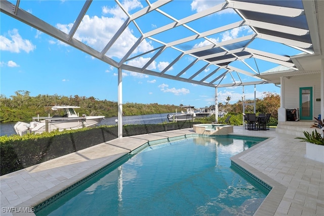 view of pool with glass enclosure, a water view, an in ground hot tub, and a patio