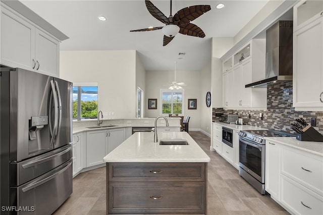 kitchen featuring an island with sink, stainless steel appliances, a healthy amount of sunlight, and wall chimney range hood