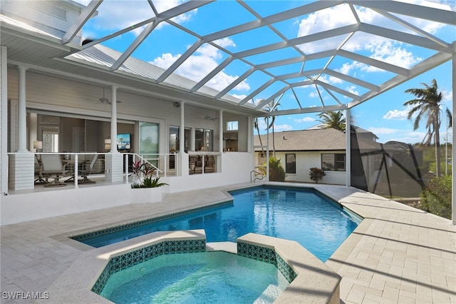 view of swimming pool featuring glass enclosure, ceiling fan, a patio area, and an in ground hot tub