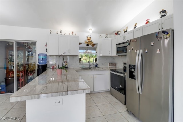 kitchen featuring kitchen peninsula, stainless steel appliances, sink, light tile patterned floors, and white cabinets