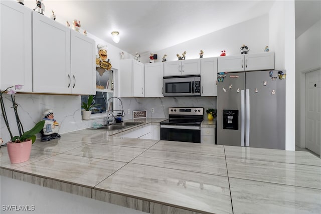 kitchen featuring sink, vaulted ceiling, white cabinetry, appliances with stainless steel finishes, and tasteful backsplash