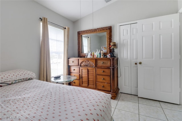 bedroom featuring a closet, light tile patterned floors, and vaulted ceiling