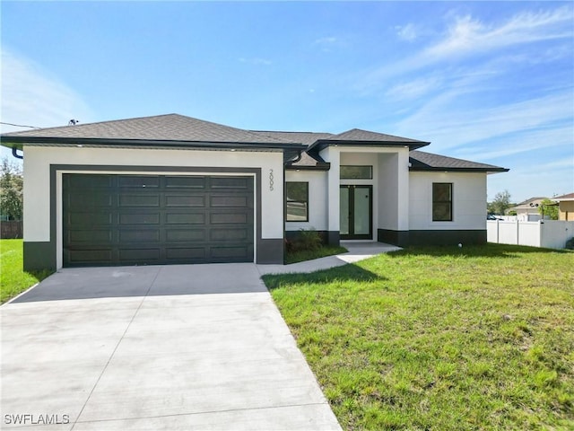 prairie-style home with an attached garage, fence, a front lawn, and stucco siding