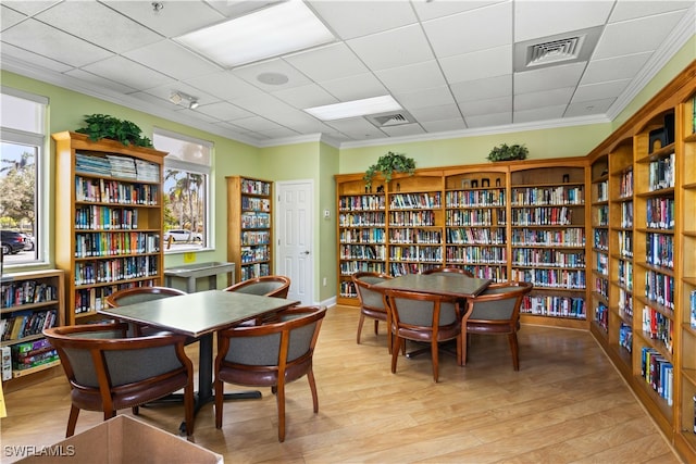 dining space featuring light hardwood / wood-style floors, crown molding, and a drop ceiling