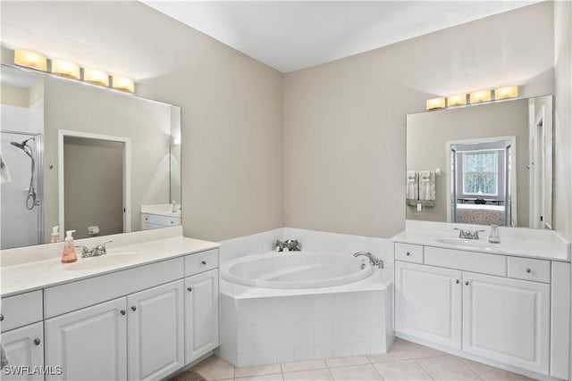 ensuite bathroom featuring a sink, two vanities, a bath, and tile patterned flooring