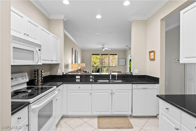 kitchen with dark countertops, ornamental molding, light tile patterned flooring, white appliances, and a sink