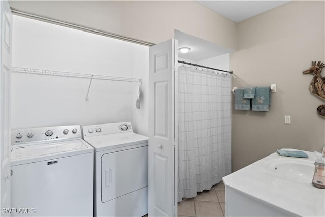 clothes washing area featuring light tile patterned flooring, laundry area, washing machine and dryer, and a sink