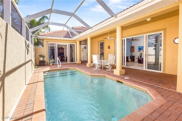 view of pool with glass enclosure, ceiling fan, and a patio area