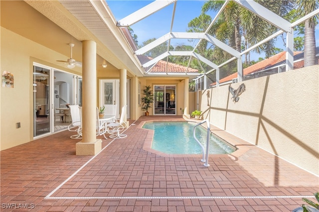 view of pool featuring a patio, glass enclosure, and ceiling fan