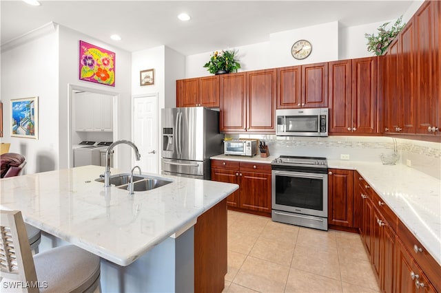 kitchen featuring a breakfast bar, sink, independent washer and dryer, appliances with stainless steel finishes, and light tile patterned flooring