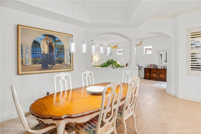 tiled dining room featuring decorative columns and crown molding