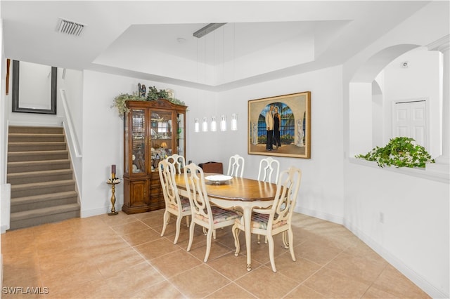 dining area featuring light tile patterned floors and a raised ceiling