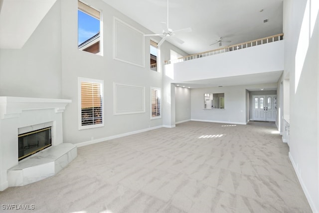 unfurnished living room featuring light colored carpet, high vaulted ceiling, ceiling fan, and a tiled fireplace