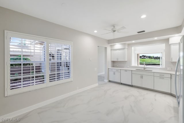 kitchen with white appliances, white cabinets, sink, ceiling fan, and decorative backsplash