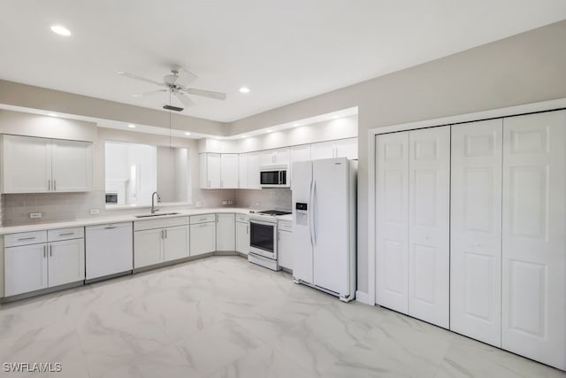 kitchen with backsplash, white cabinets, white appliances, and sink