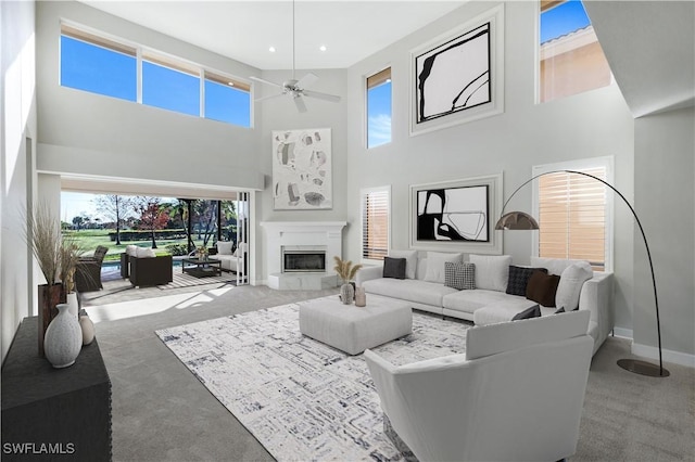 carpeted living room with a wealth of natural light, ceiling fan, and a high ceiling