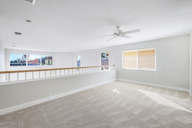 carpeted spare room featuring ceiling fan and a wealth of natural light