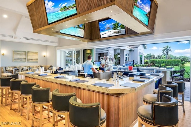 bar with a high ceiling and light wood-type flooring