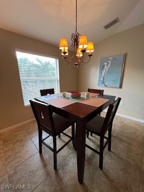 tiled dining area with vaulted ceiling and an inviting chandelier