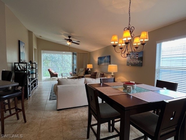 tiled dining space with ceiling fan with notable chandelier, lofted ceiling, and a wealth of natural light