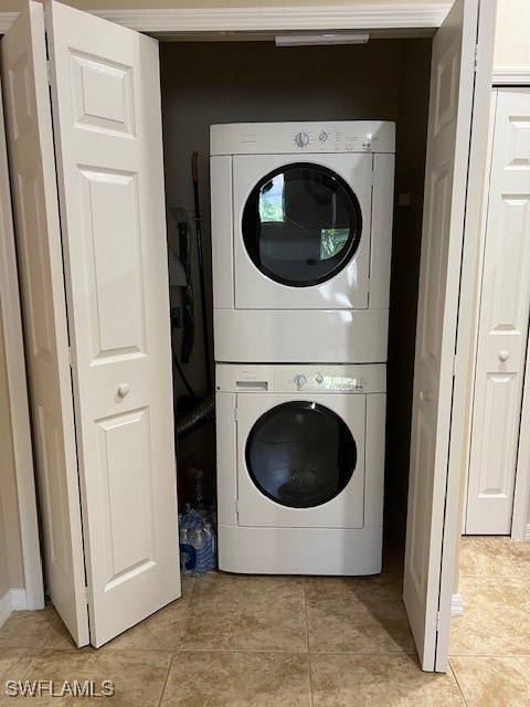 washroom with light tile patterned flooring and stacked washing maching and dryer