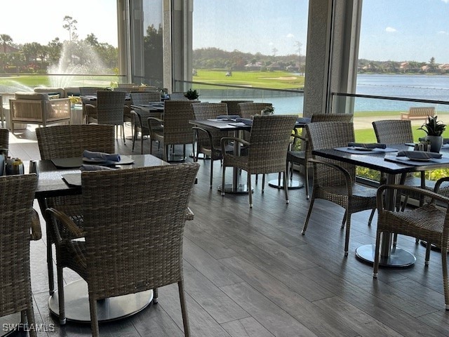 dining room with wood-type flooring, a water view, and a wealth of natural light