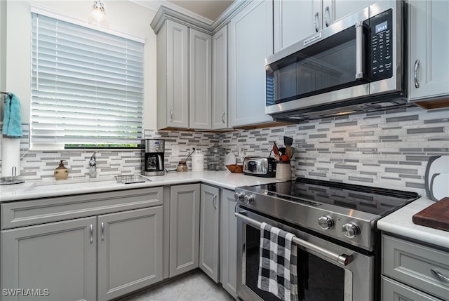 kitchen featuring gray cabinetry, sink, light tile patterned flooring, backsplash, and stainless steel appliances