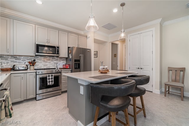 kitchen with appliances with stainless steel finishes, a center island, decorative light fixtures, gray cabinets, and crown molding