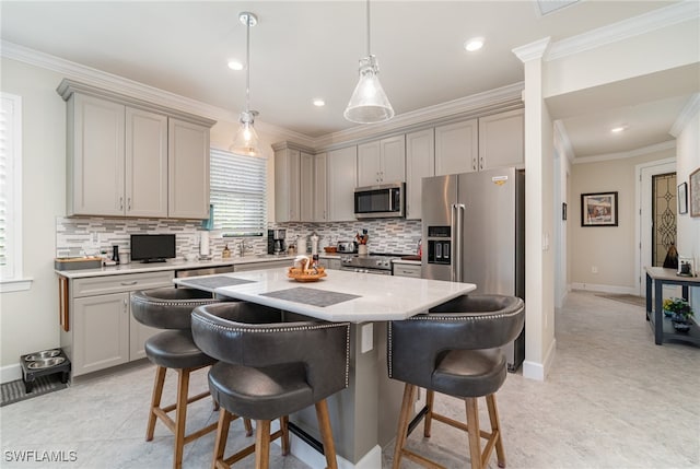 kitchen featuring gray cabinetry, crown molding, stainless steel appliances, and a center island