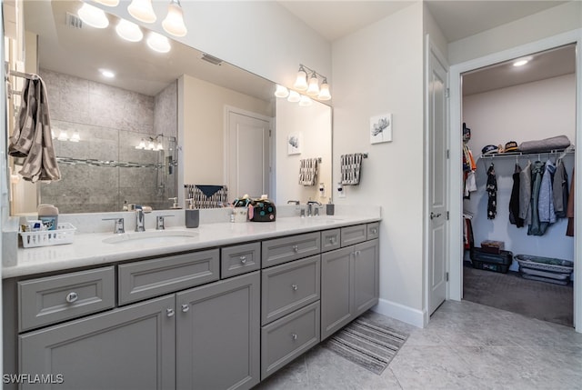 bathroom with vanity, a tile shower, and tile patterned flooring