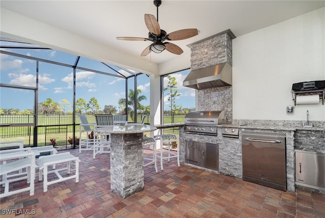 view of patio featuring a bar, grilling area, an outdoor kitchen, glass enclosure, and ceiling fan