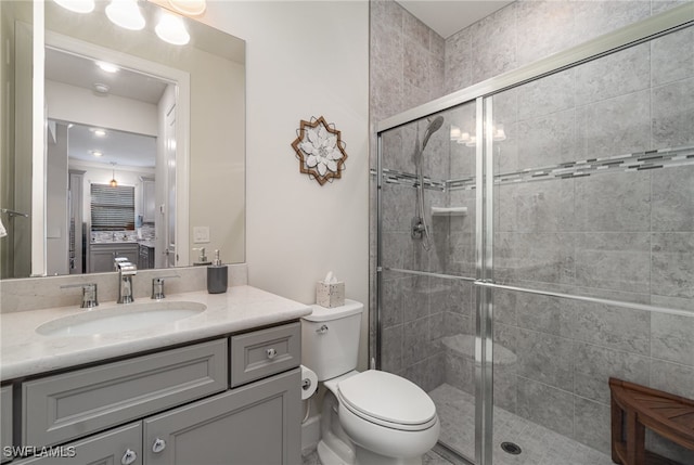 bathroom featuring vanity, walk in shower, and toilet