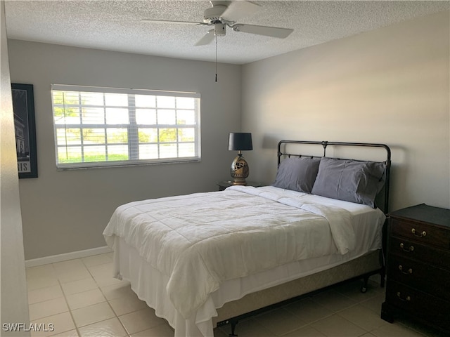 bedroom with ceiling fan, light tile patterned flooring, a textured ceiling, and multiple windows