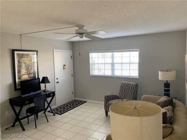 living area featuring a textured ceiling, light tile patterned floors, and ceiling fan