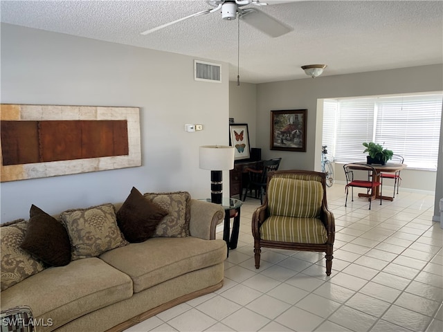 tiled living room with ceiling fan and a textured ceiling