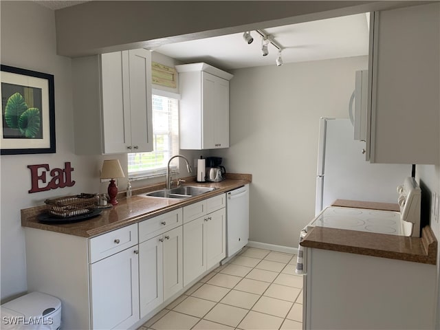 kitchen featuring track lighting, white dishwasher, sink, light tile patterned floors, and white cabinetry