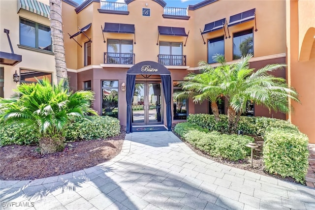 view of exterior entry with a balcony and french doors