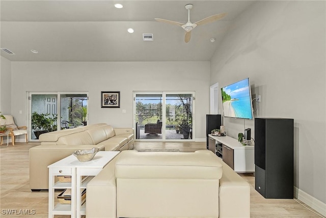 living room with ceiling fan, light hardwood / wood-style floors, and vaulted ceiling