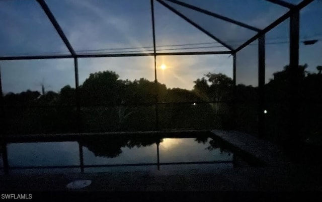 pool at dusk featuring glass enclosure