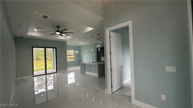 unfurnished room with sink, a tray ceiling, and ceiling fan