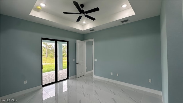 empty room featuring ceiling fan and a raised ceiling