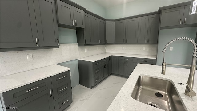 kitchen with sink, light stone counters, and backsplash