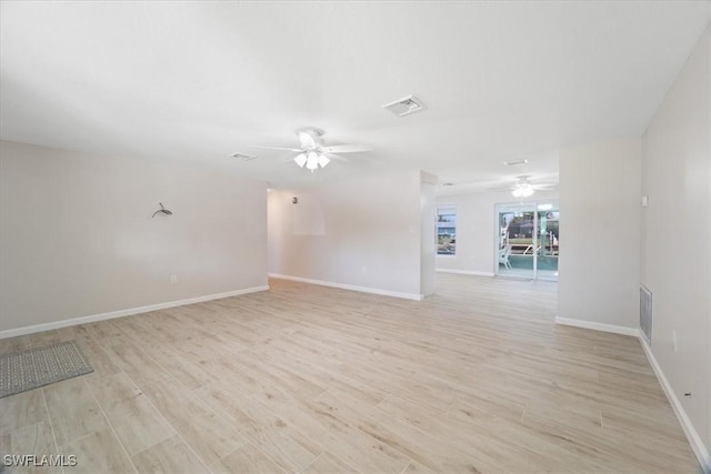 unfurnished room with baseboards, light wood-style flooring, visible vents, and a ceiling fan